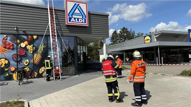 Das Foto zeigt zwei Feuerwehrleute vor dem Aldi-Markt. 