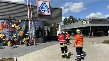 Das Foto zeigt zwei Feuerwehrleute vor dem Aldi-Markt. 