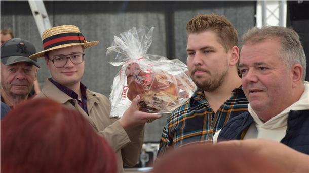 Schweinskopf-Versteigerung in Rodenkirchen: Dafür werden die Erlöse eingesetzt Der Sammler Marijano Weimar hält den Schweinskopf in der Hand und geht durch das Festzelt.