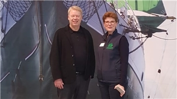 Ein Mann und eine Frau vor dem riesigen Poster der "Alexander von Humboldt II". Darüber der Slogan "Komm an Bord".