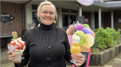 Eine Frau hält Eis in den Händen und lächelt.