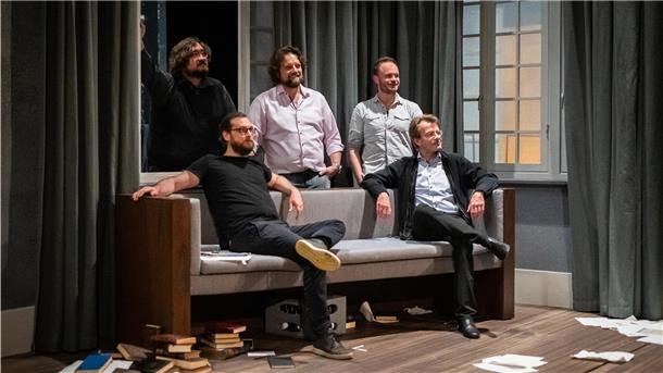Zwei Männer sitzen auf einem Sofa, drei stehen, Bühne im Stadttheater Bremerhaven.