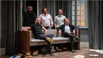Zwei Männer sitzen auf einem Sofa, drei stehen, Bühne im Stadttheater Bremerhaven.