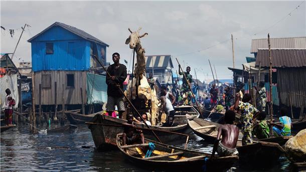 Als Herde gegen den Klimawandel Auf Kanus bewegen sich die Puppenspieler durch Teile der Stadt Lagos im Land Nigeria.