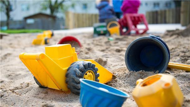 Spielzeug liegt in einem Sandkasten in einer Kindertagesstätte.