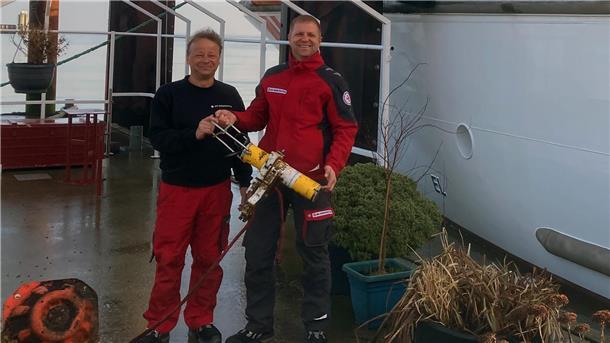 Vormann Ralf Sarközy und Maschinist Kai Schöps präsentieren ihr Fundstück vor dem Seenotrettungskreuzer „Anneliese Kramer“
