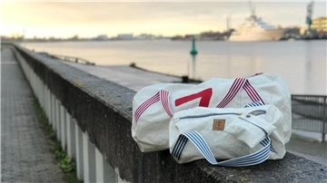 Zwei Taschen liegen auf einer Mauer