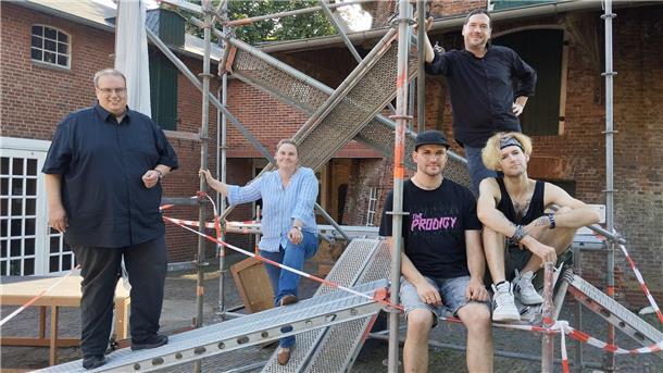 Menschen stehen und hocken auf einem Gerüst