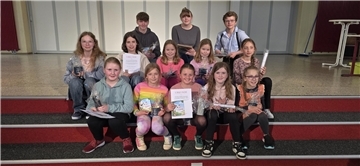 Schülerinnen und Schüler sitzen zusammen auf einer Treppe. 