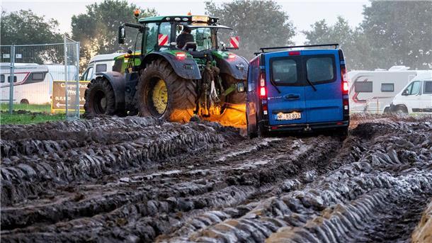 Autos werden mit Hilfe eines Traktors auf das Gelände des Heavy-Metal-Festivals in Wacken durch den Schlamm gezogen.