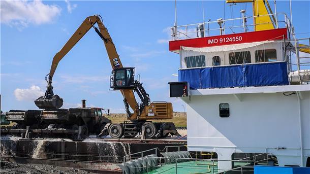 Bagger entladen am Kleilager nahe der Baustelle des LNG Terminals an der Elbe in Stade Klei ein Transportschiff.