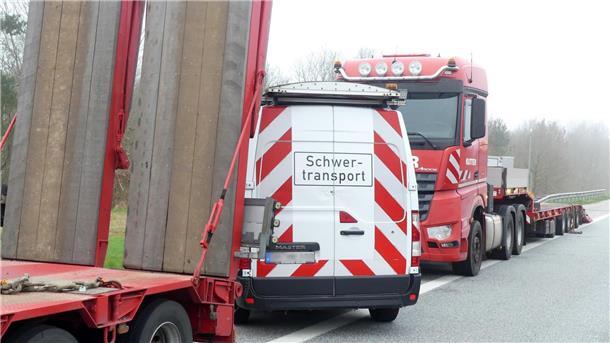 Bagger und Fräsen werden mit Tiefladern zur Baustelle geliefert. 
