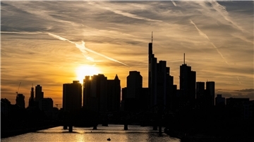 Bankentürme der Frankfurter Skyline vor einem sonnengefärbten Himmel.