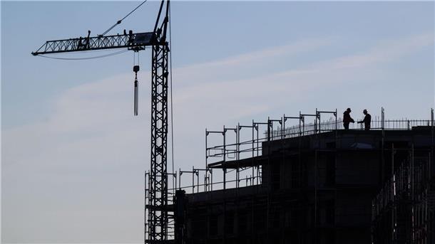 Bauarbeiter stehen auf der Baustelle eines Mehrfamilienhauses.
