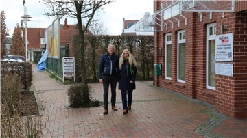 Mann und Frau auf einem Fußweg vor einem Haus.