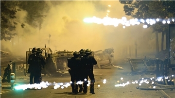 Beamte der Bereitschaftspolizei patrouillieren bei Unruhen auf einer Straße in Nanterre.