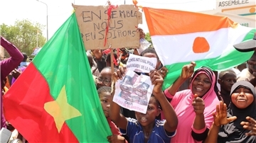 Befürworter des Putschs halten eine Flagge von Burkina Faso (l) und Niger hoch. Die beiden Länder haben einen Pakt geschlossen.