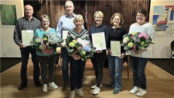 Geehrte Mitglieder des TuS Schwei mit Urkunden und Blumensträußen