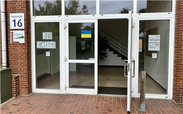 Der Eingang des Welcome Points in Dorum - Glastüren auf denen die Ukrainische Fahne klebt. 