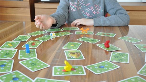Ein Kind würfelt an einem Tisch und spielt ein Spiel.