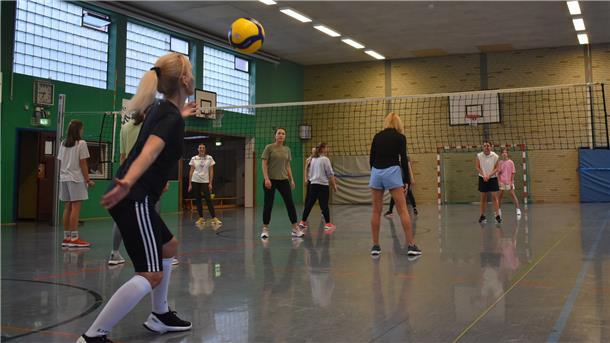 Frauen spielen in einer Turnhalle Volleyball.