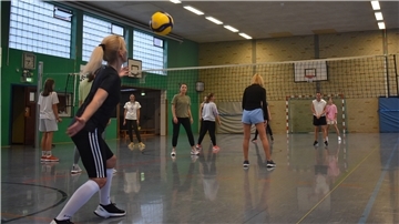 Frauen spielen in einer Turnhalle Volleyball.