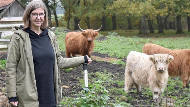 Eine Frau und im Hintergrund Kühe mit langem Fell.