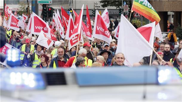 Tausende bei Demos für soziale Sicherheit in Energiekrise Bei der Demonstration in Düsseldorf gehen Teilnehmer mit Flaggen eine Straße entlang. Die Kundgebung wird von der Polizei begleitet.