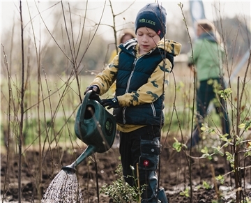 Green Action Week: Wie wertvoll ein Naschgarten für das Klima ist Ein Junge gießt mit einer Gießkanne frisch eingepflanzte Pflanzen.