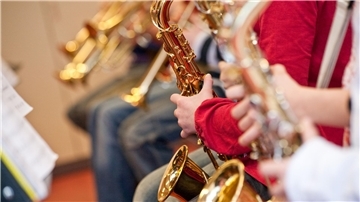Das Foto zeigt fünf Musiker, die Blechblasinstrumente spielen.