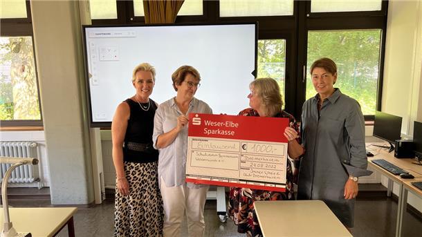 Vier Frauen halten einen Scheck.