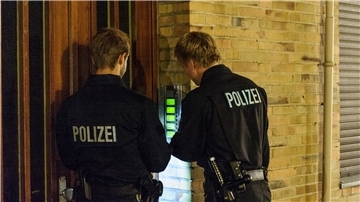 Zwei Polizisten klingeln  (Niedersachsen) an einer Haustür.