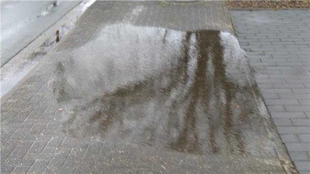 Das Foto zeigt eine Pfütze auf dem Radweg. 