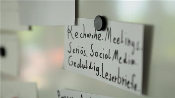 Eine Karte an einer Tafel, auf der Begriffe wie Recherche und Meetings stehen.