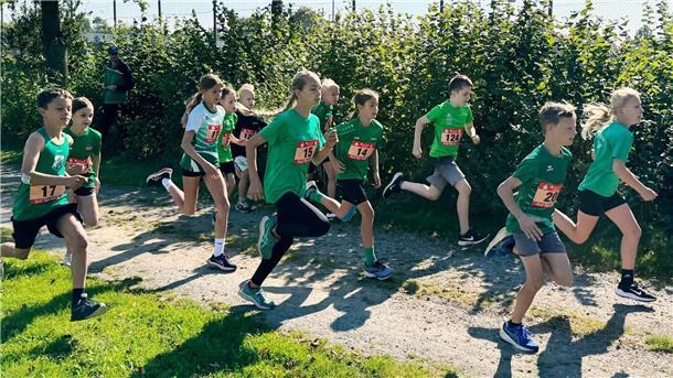 Kinder laufen in Sportkleidung auf einem Sandweg.