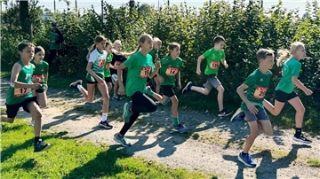 Kinder laufen in Sportkleidung auf einem Sandweg.