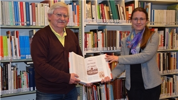 Stadtarchivleiterin Dr. Julia Kahleyß und Historiker Dr. Dirk J. Peters halten ein Buch.