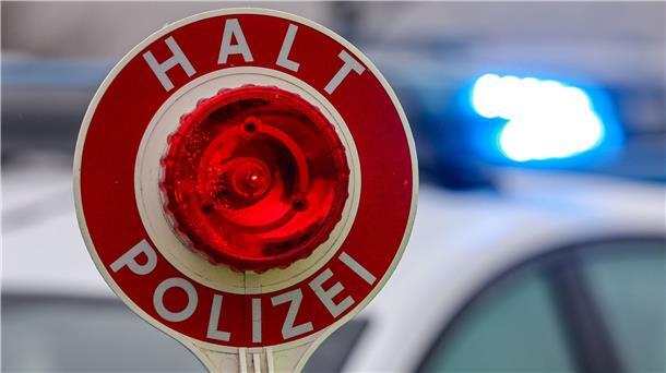 Ein Polizist hält eine Polizeikelle für eine Kontrolle in der Hand. 