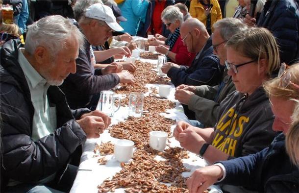 An einer Tafel pulen Teilnehmer an Krabben.