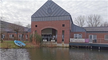 Gebäude von außen, davor ein Gewässer