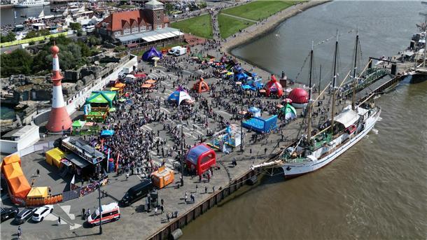 Luftfoto zu einer Veranstaltung, die auf einem Platz an der Weser stattfindet. Auch ein Schiff ist zu sehen. 