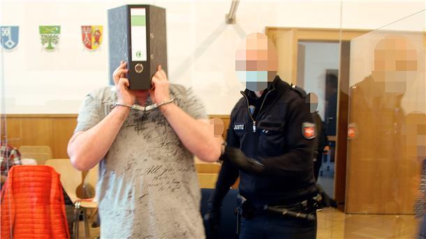 Beim ersten Prozesstag im Juli dieses Jahres wurde der Angeklagte in Handschellen in den Gerichtssaal geführt. Er verbarg sein Gesicht hinter einem Aktenordner.