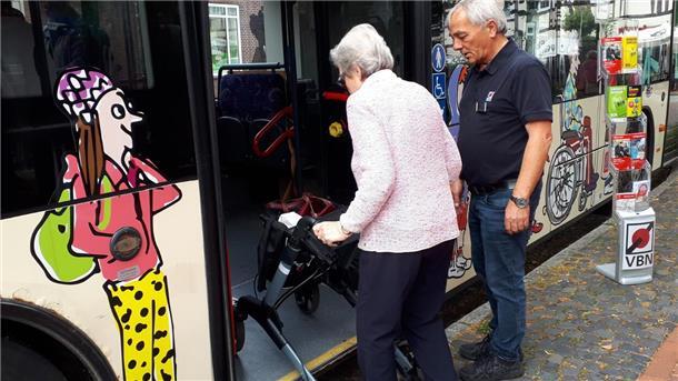 Eine Frau mit Rollator steigt in einen Bus. 