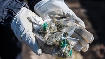 Eine Polizistin hält Tüten mit Marihuana in die Kamera.
