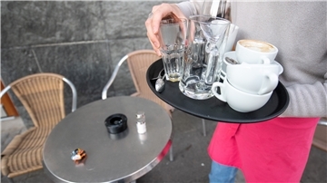 Ein Kellner räumt einen Tisch in einem Restaurant ab.