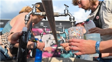 Besucher füllen beim Hurricane Festival ihre Becher und Trinkflaschen mit Wasser auf. In Deutschland steigen die Temperaturen - und die Ozon-Werte.