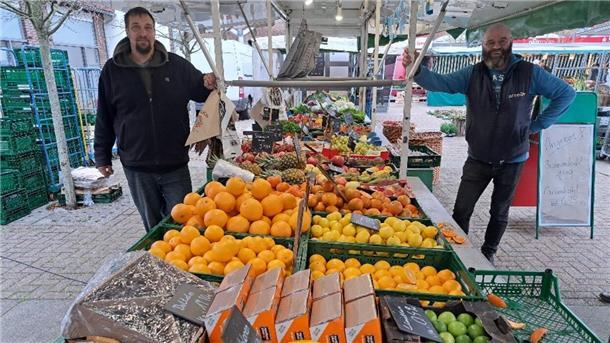 Zwei Männer an ihrem Stand auf dem Wochenmarkt.