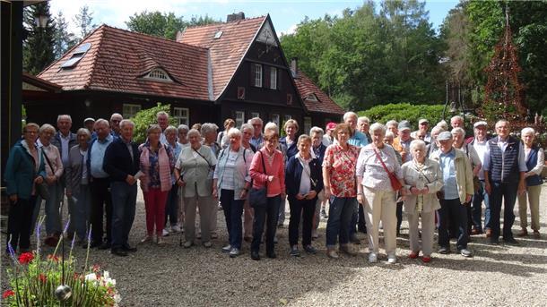 45 Männer und Frauen stehen vor einem Haus.