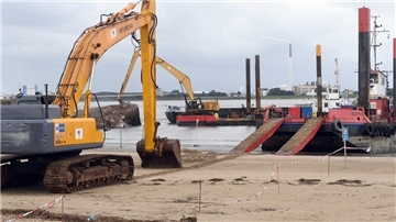 Ein Bagger steht am Strand