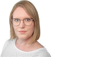 Blonde Frau mit dunkler Brille schaut direkt in die Kamera